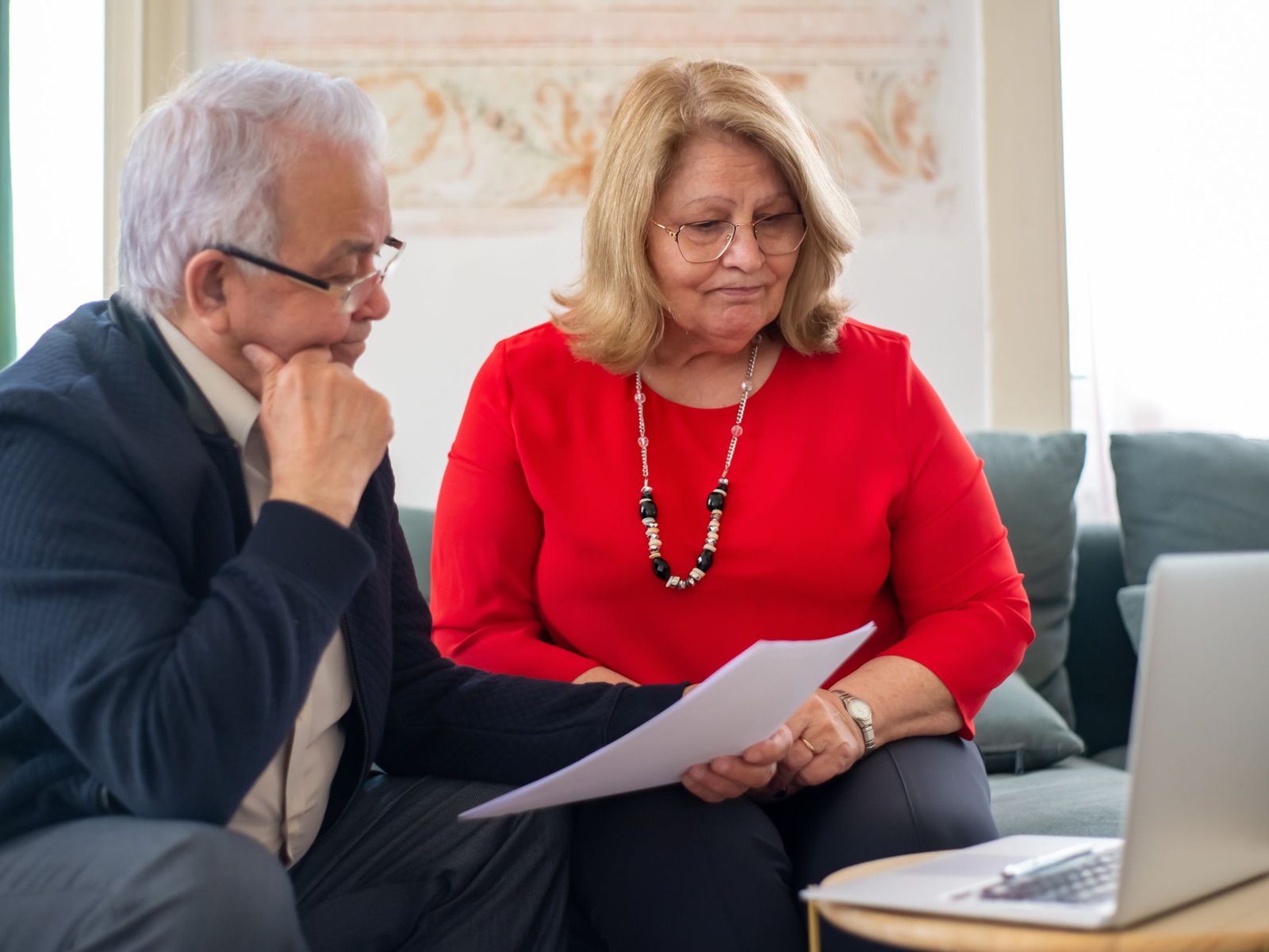 Une conseillère SMI mutuelle accompagne un couple senior dans un bureau lumineux, dossier santé en main.